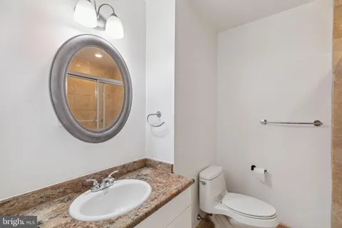 a bathroom with a granite countertop toilet a sink and a mirror