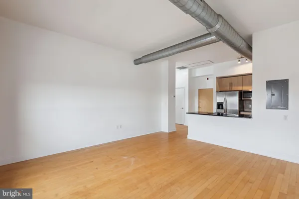 a view of a big room with wooden floor and a kitchen