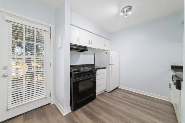 an empty room with wooden floor cabinets and windows