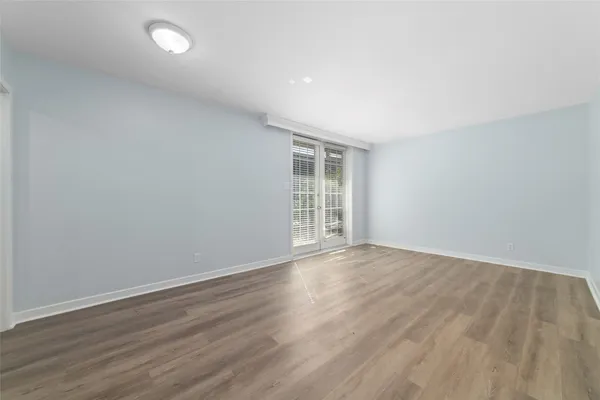 a view of an empty room with wooden floor and windows