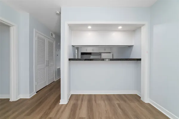 a view of a room with wooden floor and a kitchen space