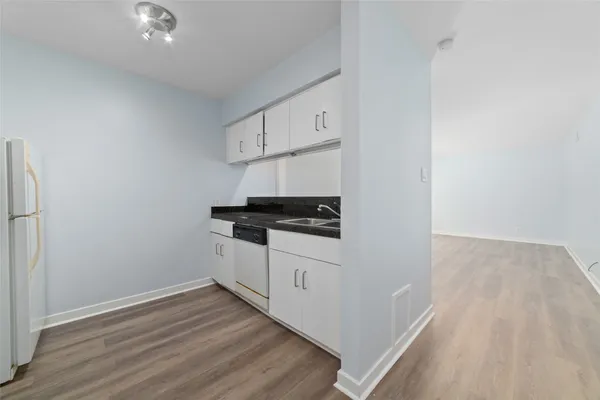 a kitchen with a refrigerator and white cabinets