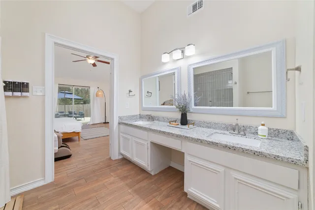 a bathroom with a granite countertop sink mirror and wooden floor