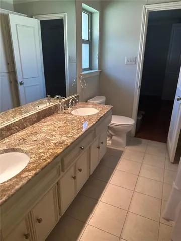a bathroom with a granite countertop sink a toilet and a mirror