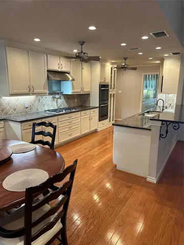a kitchen with stainless steel appliances granite countertop a table chairs sink refrigerator and microwave
