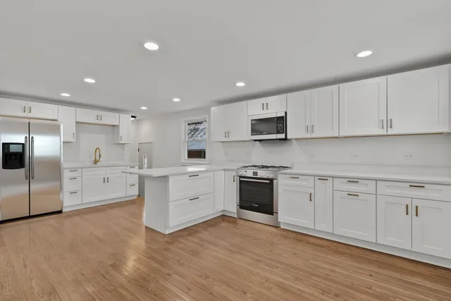 a large kitchen with cabinets wooden floor and stainless steel appliances