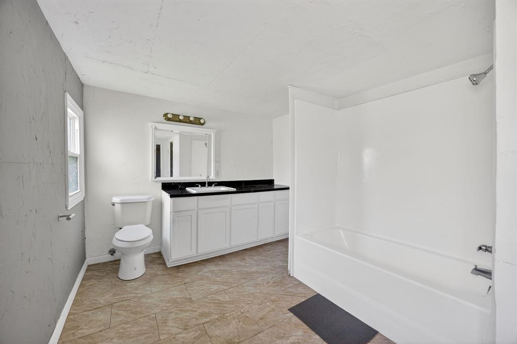 130 Center Street Nevada, TX 75173 - Photo 28 of 32 a bathroom with a white tub shower vanity and a toilet