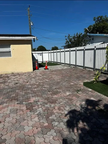 view of a refrigerator in kitchen and an empty room with wooden floor