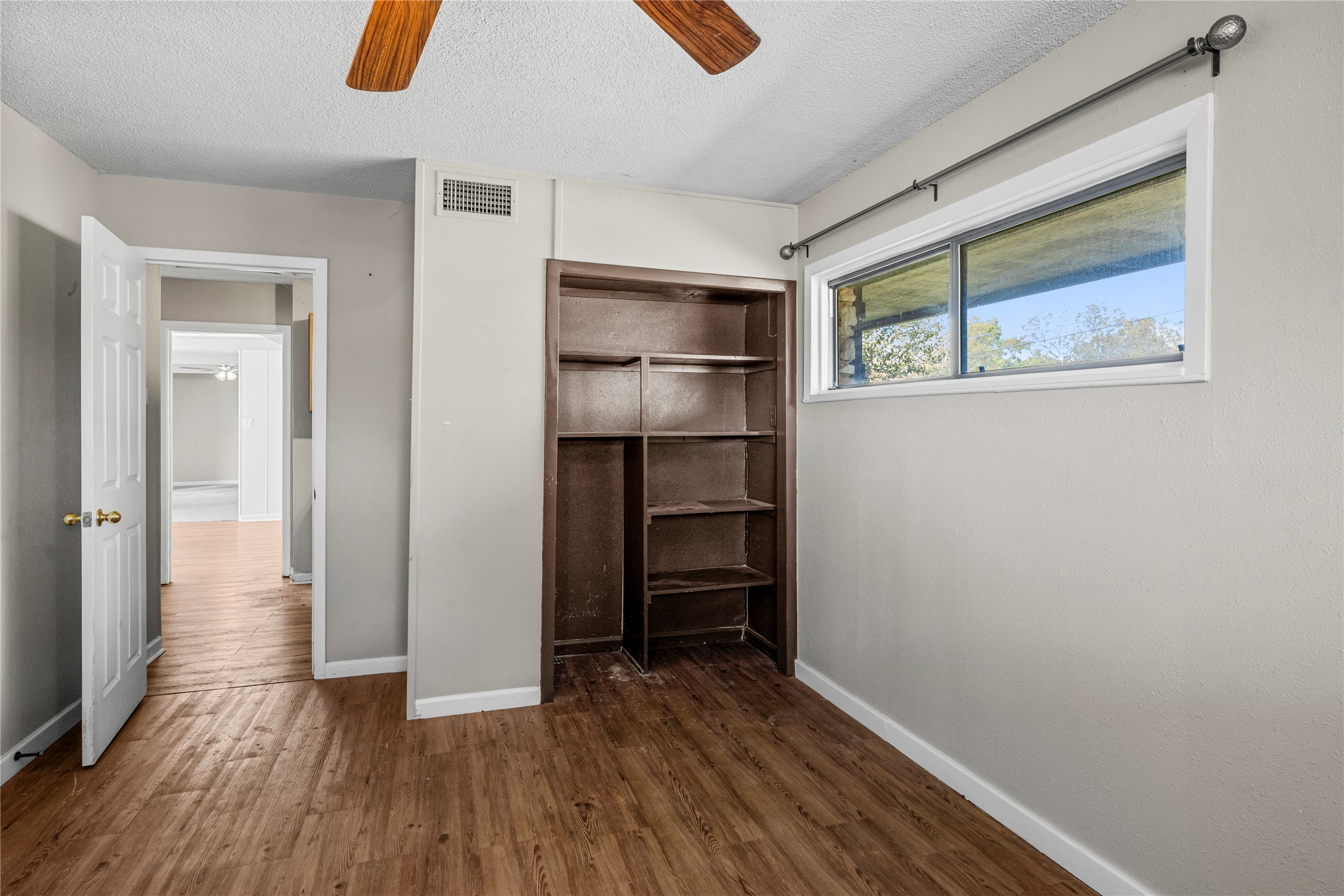 1401 Brazos Street Marble Falls, TX 78654 - Photo 18 of 23 Unfurnished bedroom featuring a textured ceiling, dark wood finished floors, a closet, and a ceiling fan