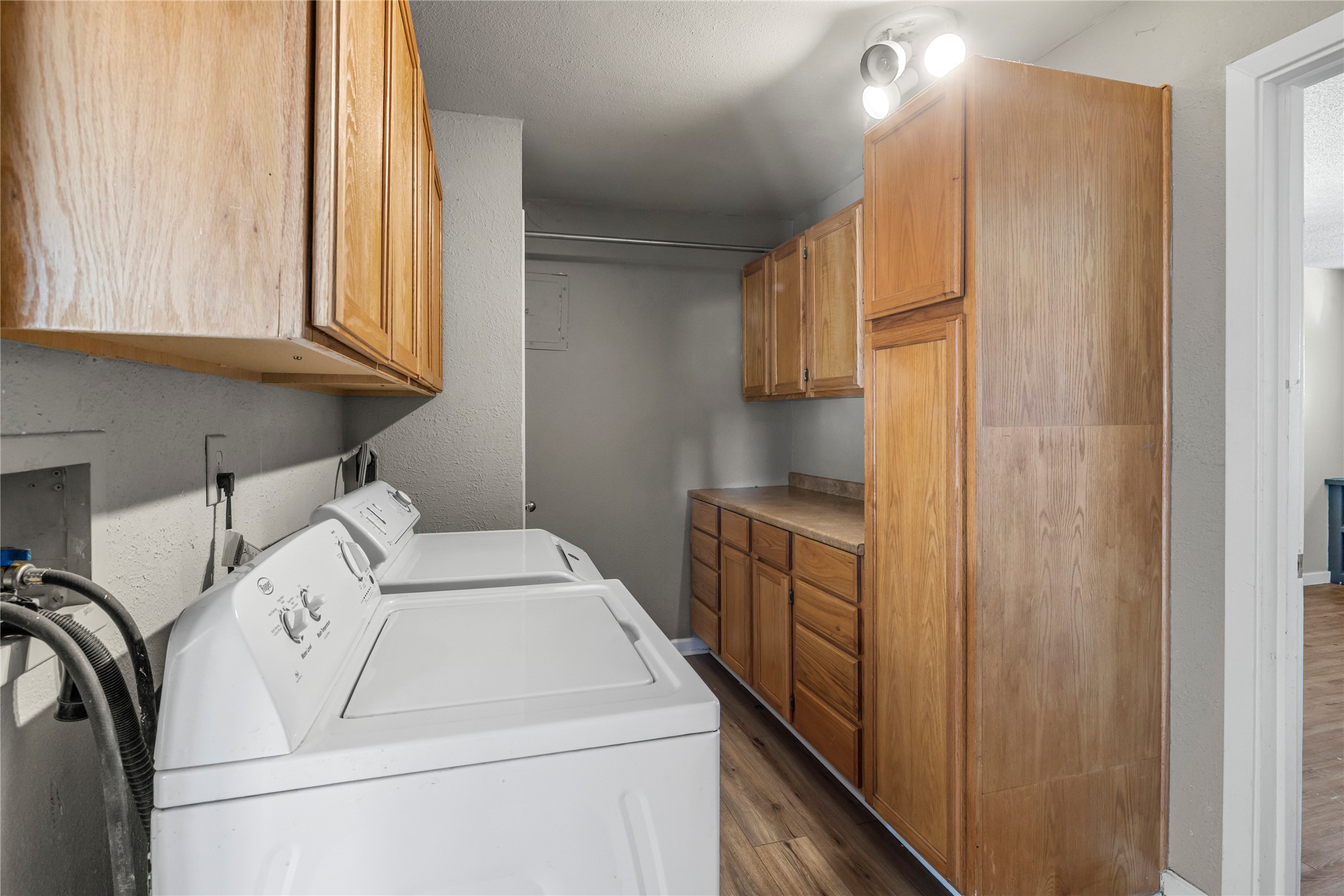 1401 Brazos Street Marble Falls, TX 78654 - Photo 19 of 23 Laundry room featuring cabinet space, a textured wall, dark wood-style floors, and washer and dryer