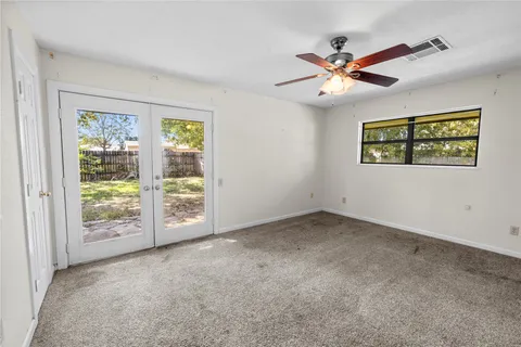 an empty room with windows and fan