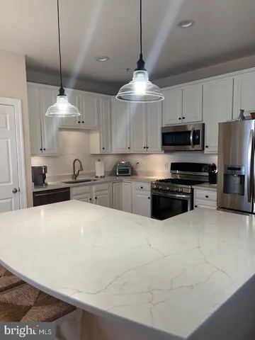 a large kitchen with stainless steel appliances a stove a refrigerator a sink and a microwave