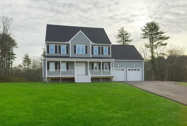 a front view of a house with a yard and large trees