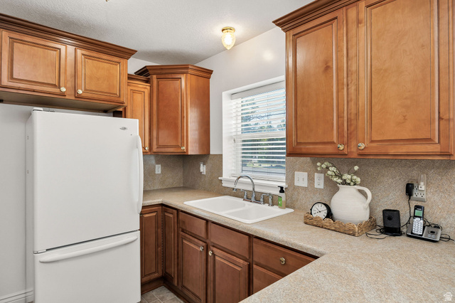 80 North 500 West Logan, UT 84321 - Photo 6 of 36 Wood-finish cabinetry with crown molding, laminate countertops, and a double basin sink with a chrome faucet