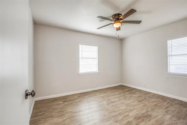 an view of an empty room with a ceiling fan and window