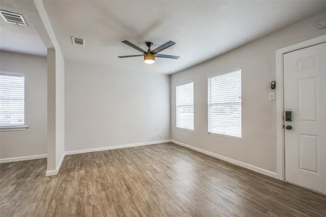 a view of empty room with wooden floor and fan