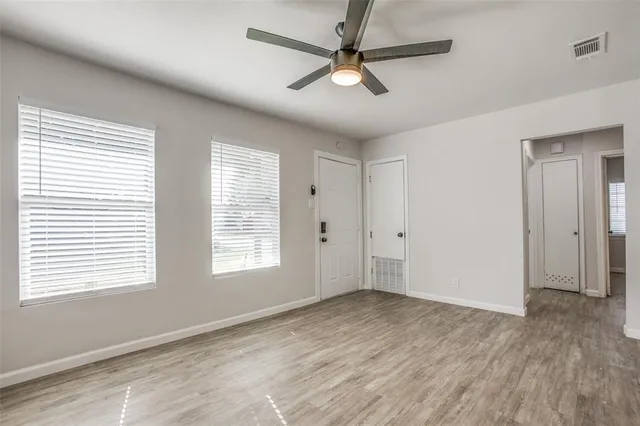 a view of an empty room with a window and a ceiling fan
