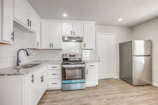 a kitchen with stainless steel appliances granite countertop a refrigerator sink and stove