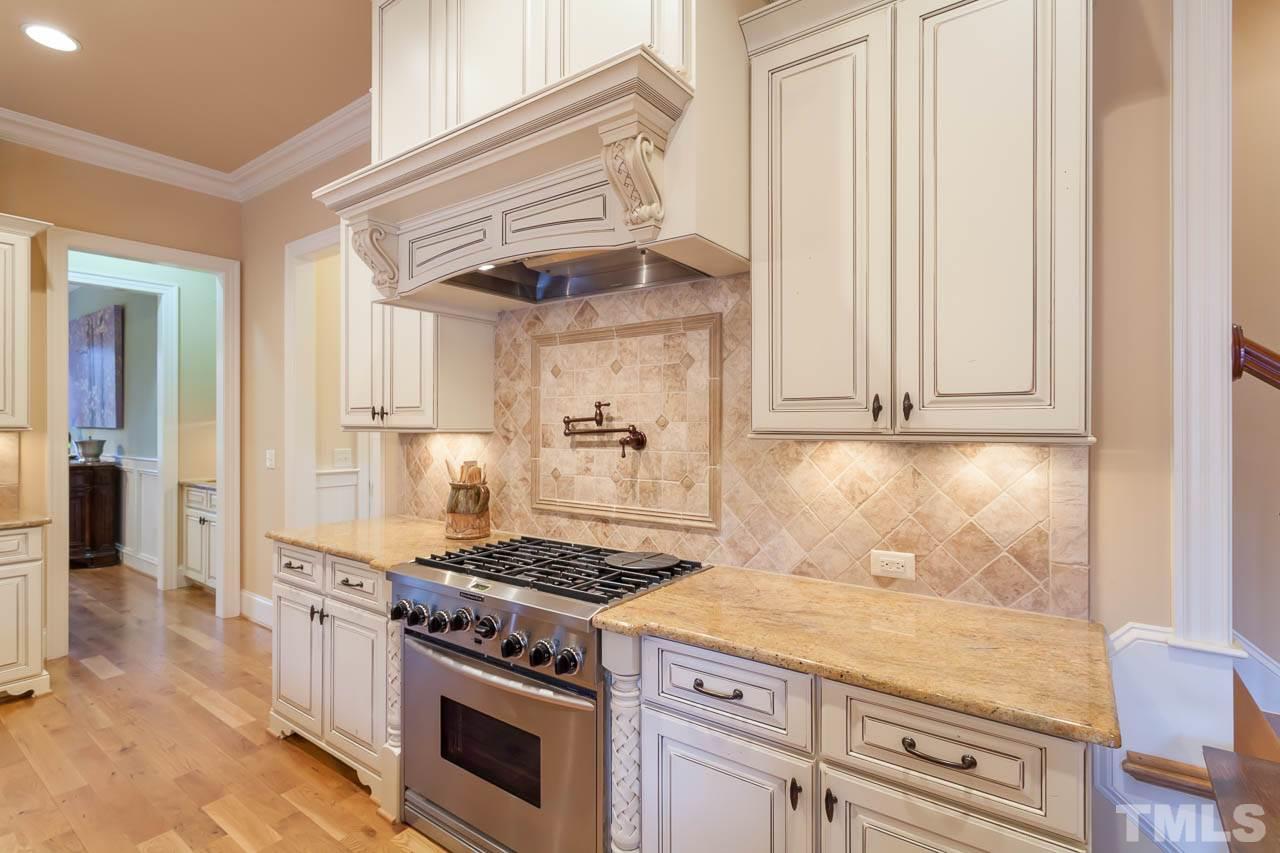 821 Keith Road Wake Forest, NC 27587 - Photo 5 of 25 The kitchen offers furniture grade cabinets with custom finishes. Notice the details on either side of the gas range. There is also a tile backsplash.