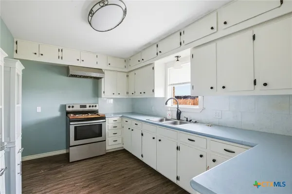 a kitchen with granite countertop a sink a stove and cabinets