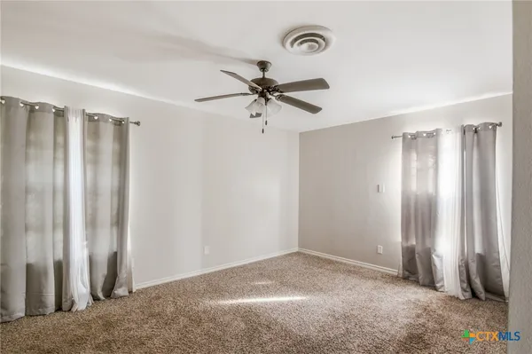 an empty room with windows and fan