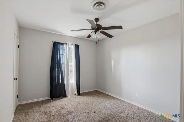 an empty room with windows and fan
