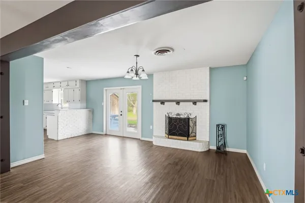 an empty room with wooden floor fireplace and windows