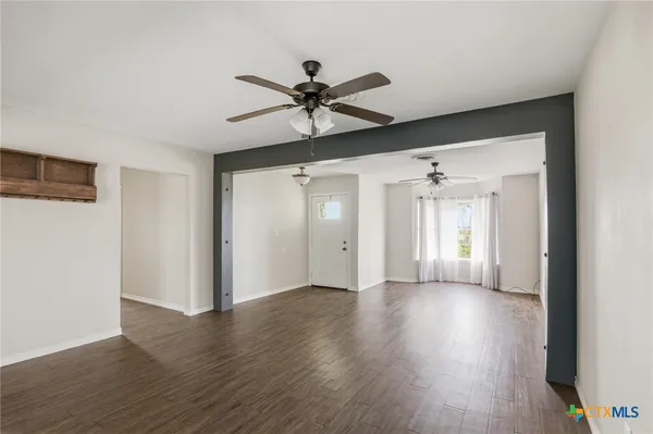 a view of an empty room with a window and wooden floor