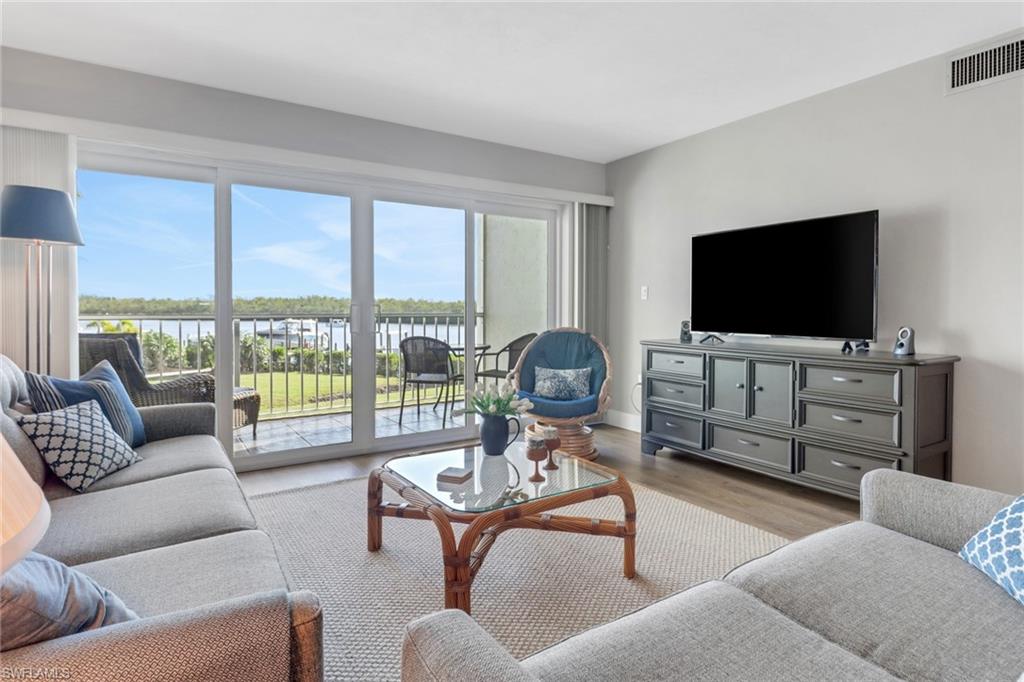 309 Goodlette-Frank Road, Unit A305 Naples, FL 34102 - Photo 3 of 10 Living room with visible vents, a healthy amount of sunlight, a water view, and wood finished floors