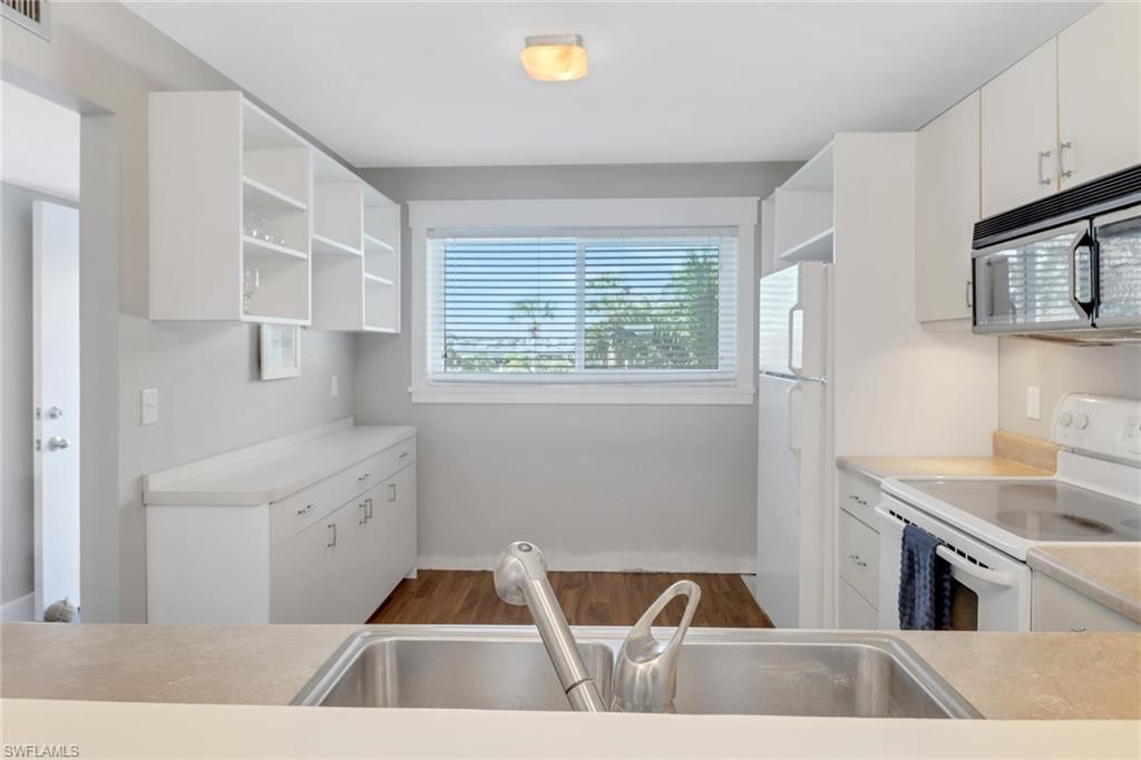 309 Goodlette-Frank Road, Unit A305 Naples, FL 34102 - Photo 5 of 10 Kitchen featuring a sink, white appliances, white cabinetry, and open shelves