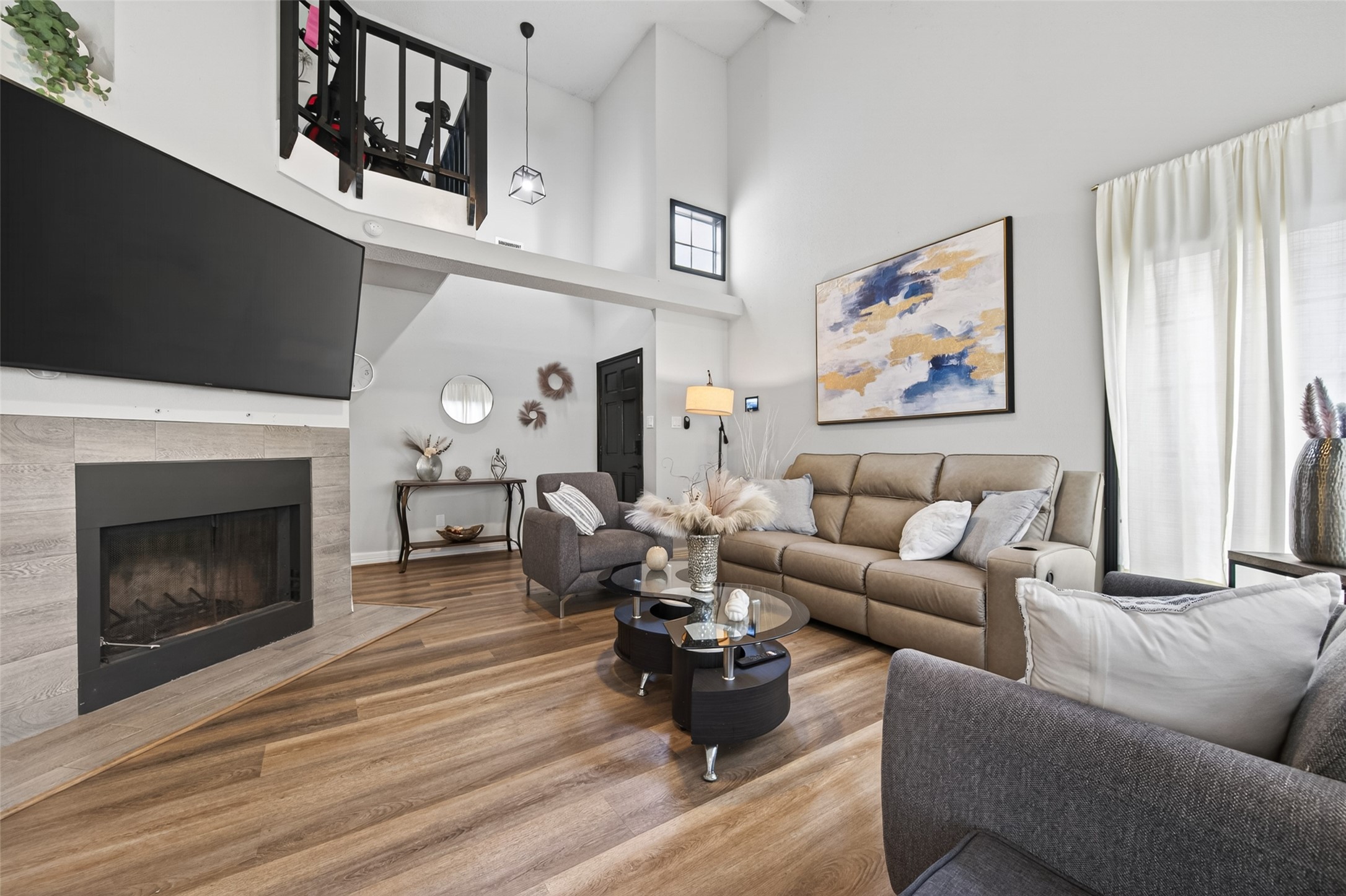 18446 North Willow Bluff Road Katy, TX 77449 - Photo 8 of 33 This inviting living room features high ceilings and abundant natural light. It includes a cozy fireplace, modern decor, and a mix of comfortable seating, perfect for relaxation or entertaining.