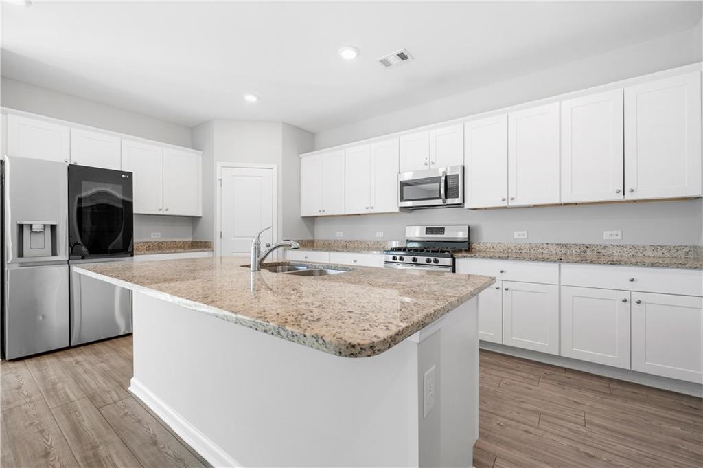 4646 Waxwing Street Hoschton, GA 30548 - Photo 12 of 36 a kitchen with stainless steel appliances granite countertop a sink stove and microwave