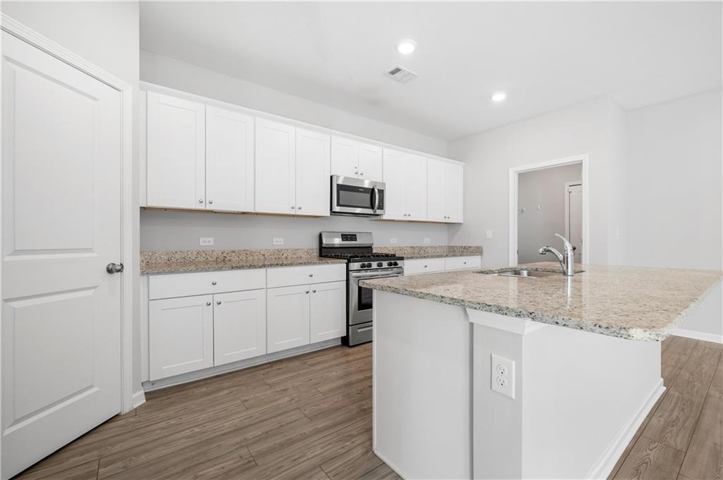4646 Waxwing Street Hoschton, GA 30548 - Photo 13 of 36 a kitchen with granite countertop white cabinets sink and stainless steel appliances