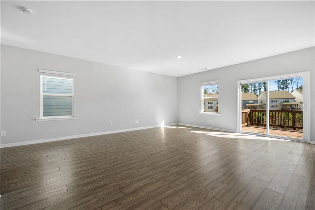 4646 Waxwing Street Hoschton, GA 30548 - Photo 10 of 36 a view of an empty room with wooden floor and a window