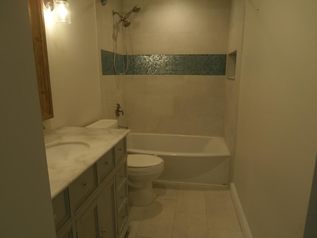 157 Yacht Club Way, Unit 201 CORNER Hypoluxo, FL 33462 - Photo 11 of 24 a bathroom with a granite countertop sink a toilet and shower