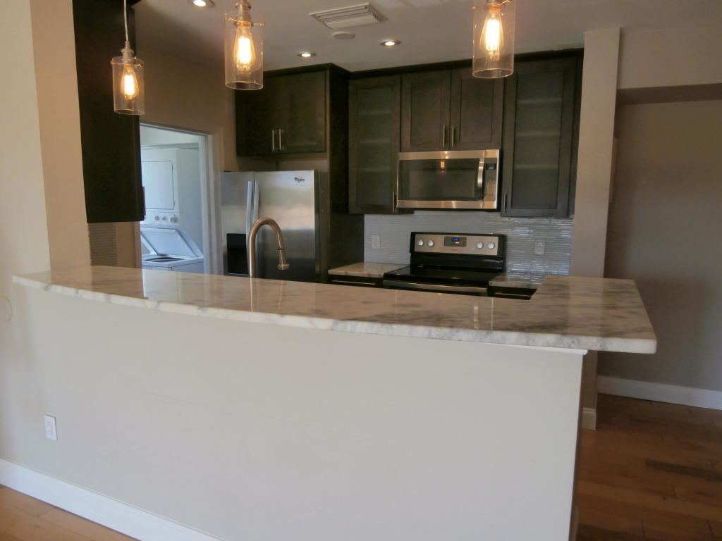 157 Yacht Club Way, Unit 201 CORNER Hypoluxo, FL 33462 - Photo 4 of 24 a kitchen with stainless steel appliances a refrigerator and a stove top oven