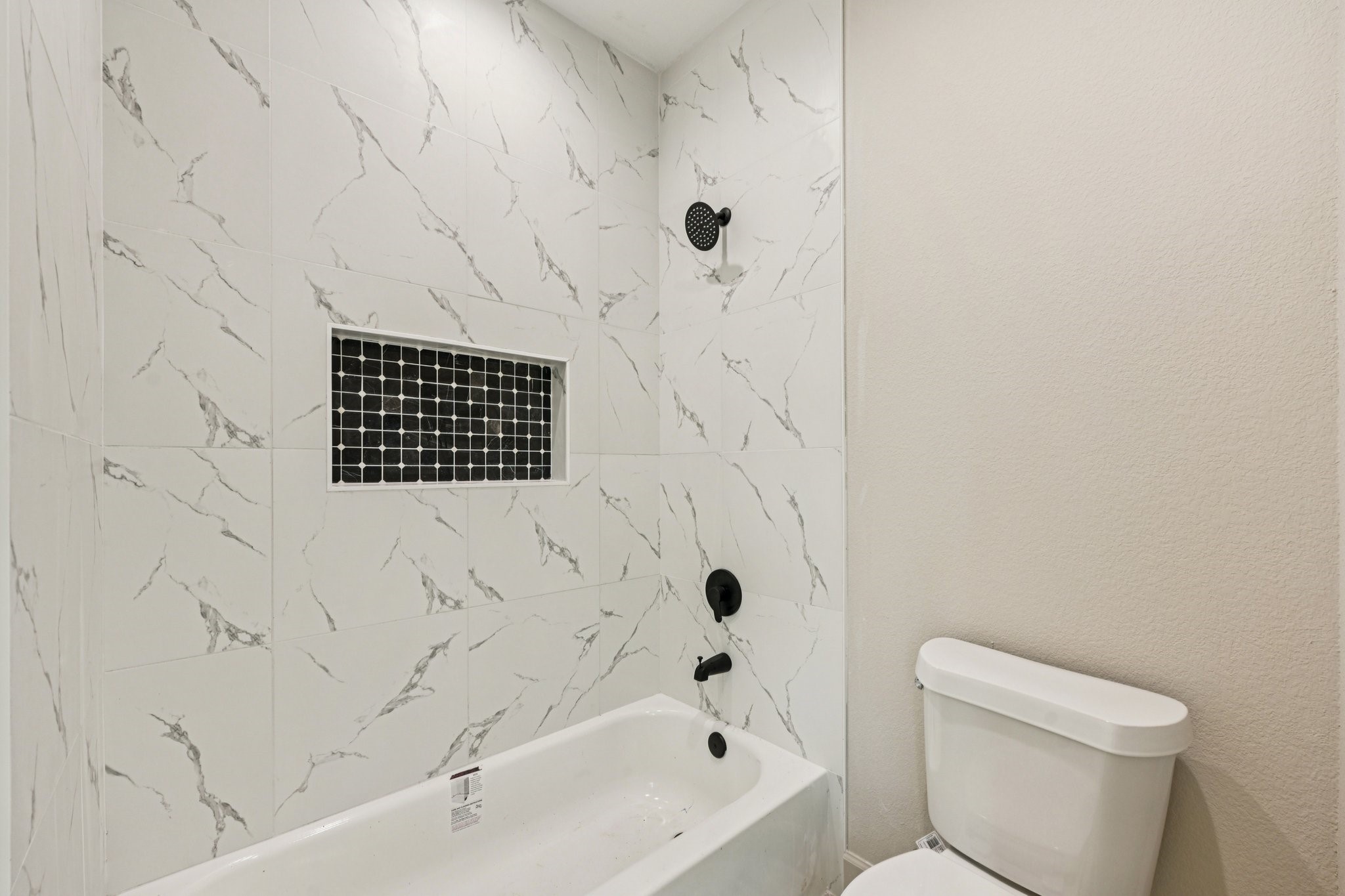 15132 Coaltown Road Willis, TX 77378 - Photo 18 of 29 Modern tub and shower with black shower head. A built-in niche with dark mosaic tiles.
