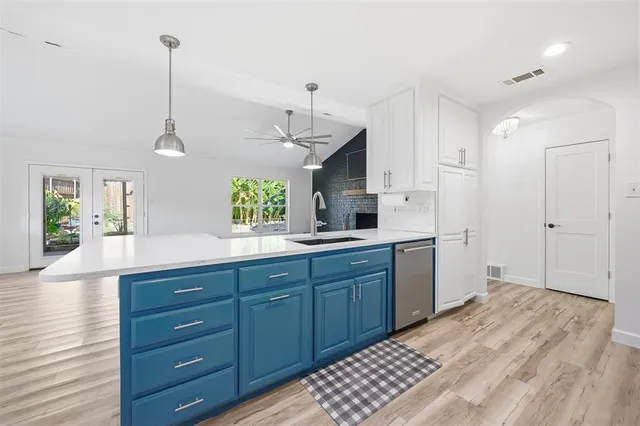 a kitchen with a sink and dishwasher with wooden floor