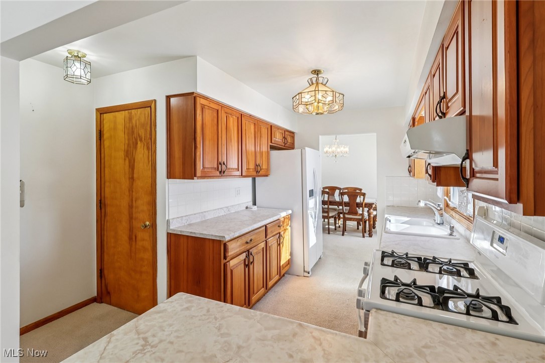 970 Eastern Road Doylestown, OH 44230 - Photo 11 of 49 Kitchen featuring brown cabinets, a chandelier, light carpet, light countertops, and decorative backsplash