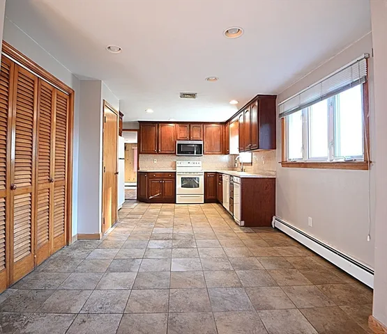 a large kitchen with stainless steel appliances granite countertop a refrigerator and a stove top oven