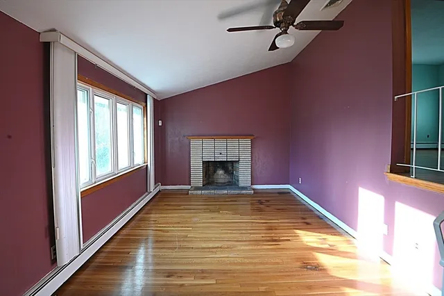 a view of a livingroom with a fireplace window and wooden floor