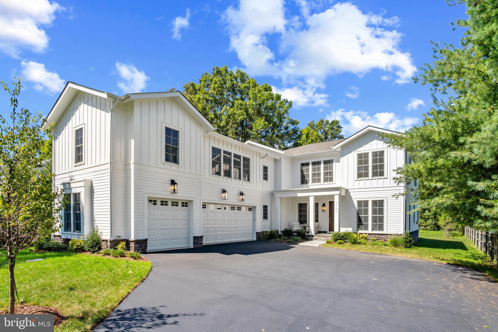 a front view of a house with a garden and trees