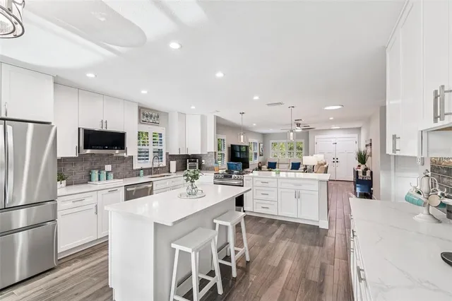 a kitchen with stainless steel appliances kitchen island granite countertop a wooden floor and white cabinets