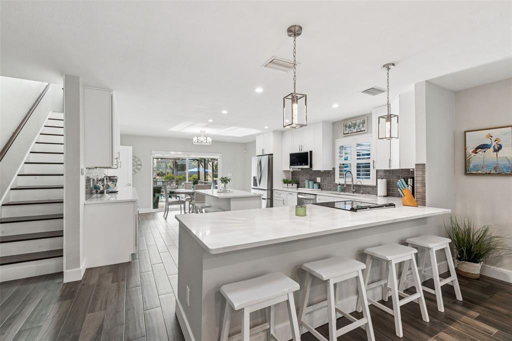 5809 Rio Drive New Port Richey, FL 34652 - Photo 13 of 61 a kitchen with stainless steel appliances kitchen island granite countertop a wooden floor and white cabinets