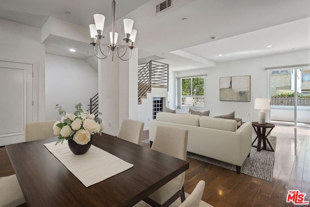 a living room with couches a coffee table and a chandelier with wooden floor