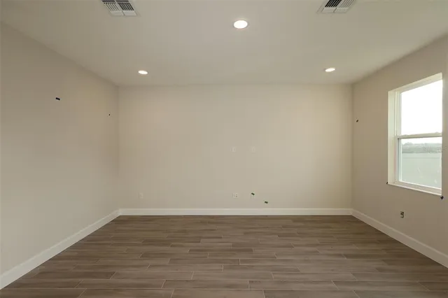 a view of empty room with wooden floor and fan
