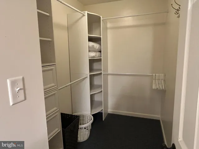 a walk in closet with wooden floor