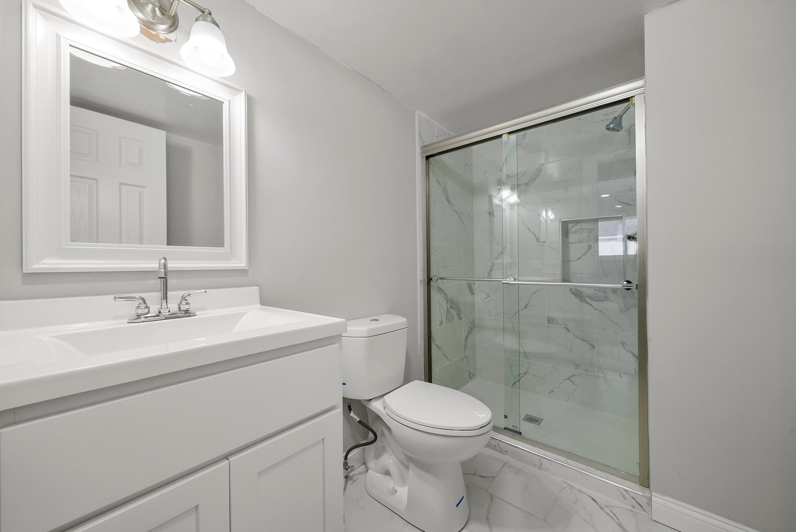 17522 Wright Street Lansing, IL 60438 - Photo 17 of 21 a bathroom with a toilet a sink a glass door a shower and a mirror