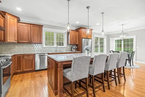 a open kitchen with granite countertop a stove a sink a dining table and chairs