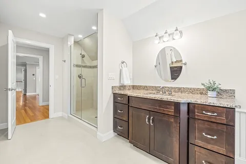 a bathroom with a granite countertop sink a mirror and a shower